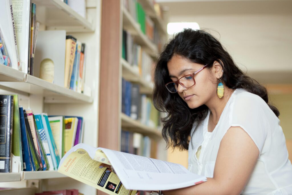 A young woman studies in a library, focusing on her reading materials.